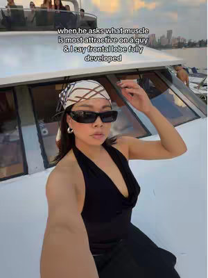 A woman in sunglasses and a headscarf, seated on a boat, smiles at the camera. Text overlay indicates the video's tone.