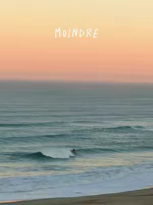 An ocean scene with a gradient sky. Above the water with the sea, sky, and beach. There is a surfer riding a wave.