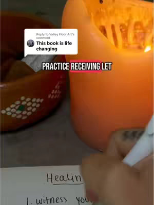 The image shows a hand writing on white paper with text that says 'Healing' and some bullet points. A lit candle and a decorative wooden bowl are also partially visible in the background.