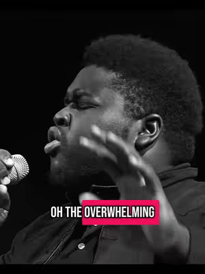 A black and white photo featuring a Black man with a short afro, singing into a microphone. His face is contorted in an expression of intense emotion. A text overlay runs across the bottom, highlighted by a pink rectangle.