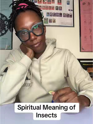 A woman with locs wearing glasses and a hoodie is seated looking at the camera, with the overlayed text Spiritual Meaning of Insects.