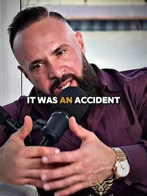 The cover image shows a man with short, dark hair and a beard, wearing a maroon shirt and a gold wristwatch. He's holding a microphone in his hands, positioned close to his mouth as if mid-sentence. The text overlay reads 'IT WAS AN ACCIDENT', appearing in a sans-serif font at the lower-middle part of the image across the man's chest.