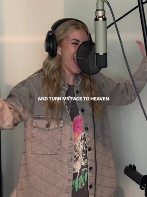 The image features a woman in a recording studio, singing with her mouth open wide while wearing headphones and looking up. A microphone is positioned in front of her, and text overlays the image. The background appears to be a plain wall, with a mic stand to her right and part of a stand up microphone to create a symmetrical composition.