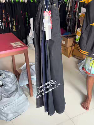 The cover image shows a vertical display of several pairs of dark-colored baggy jeans hanging in a shop. The jeans are of different shades of black and blue. In front of the jeans, there is a white tag with some text. The background is blurred, suggesting they are in a retail environment with racks of clothing. At bottom right, there is a foot.