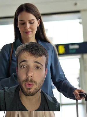 The cover image shows a man filming himself with a phone camera while standing in front of a woman. The man is in the foreground, with the woman slightly out of focus in the background. The setting appears to be an airport, with a luggage cart and overhead signs visible.