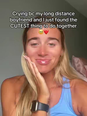 A woman with long blonde hair and fair skin is framed in a close-up, looking at the camera with a slight smile and her hand gently touching her cheek. The background has a soft, natural light, giving a diffused look, with a light blue tank top, and a watch. Text overlays are near the top of the image, conveying emotional context.