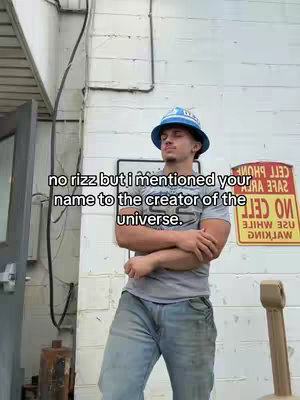A young man wearing a blue bucket hat and a grey t-shirt stands outside, leaning slightly with arms crossed and eyes closed. Text overlays the image, and the background includes a white wall.