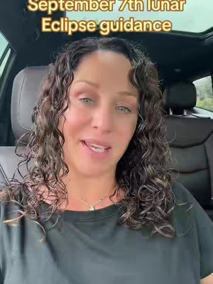A woman with curly hair is seated in a car, facing the camera. She is wearing a black shirt, and the background shows the interior of the car and a glimpse of the outside world. Text overlay on the top right corner that says: "September 7th lunar Eclipse guidance"