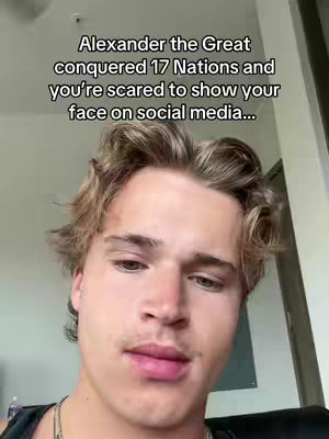 A young man with light-colored hair and a slight smile is centered in the frame. Text overlayed on the image reads, "Alexander the Great conquered 17 Nations and you're scared to show your face on social media..."
