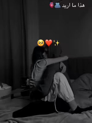 The cover image shows a black and white photo of a couple embracing in a room. A person is wrapped in the arms of their partner, both appear to be sitting on a bed. The lighting is soft and the atmosphere intimate. A text overlay in Arabic appears on the upper right corner, along with some emojis.