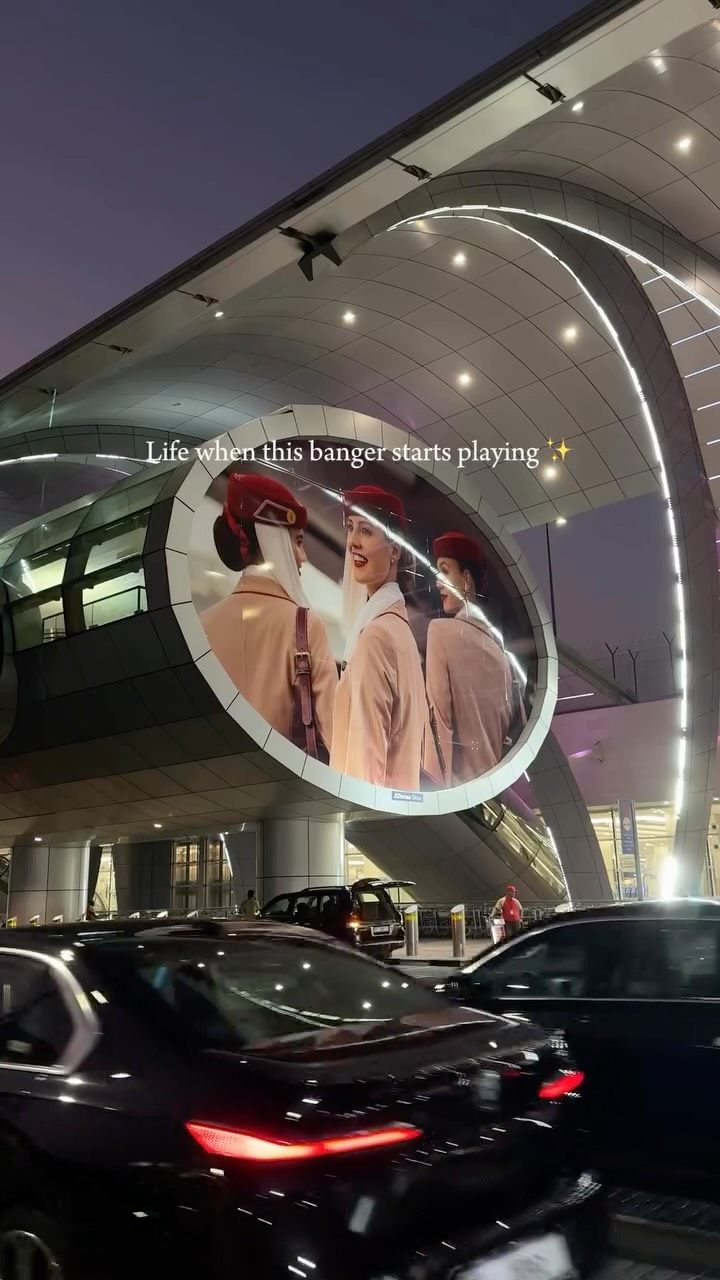 The cover image features a large advertisement for Emirates airlines, within a circular frame, surrounded by a building structure. Lights from the structure create an aesthetic appearance, and cars are visible moving in the foreground.