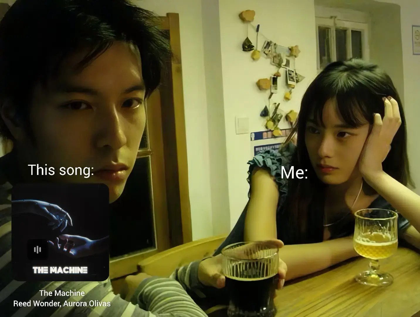 A split-screen style image featuring a man on the left side looking directly at the camera with a serious expression. Next to him on the right, a woman rests her chin on her hand, looking thoughtful. A half-empty glass of a dark liquid sits in her hand, in front of her. In the bottom left, an album cover graphic is displayed, containing an image of hands and the words 'THE MACHINE'. The background shows a warmly lit interior with a table and a blurry scene possibly suggesting a domestic environment.