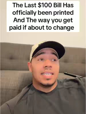 A man with brown skin wearing a baseball cap looks to the side while sitting on a grey couch. Text overlay at the top talks about changes in payments with the end of the $100 bill.
