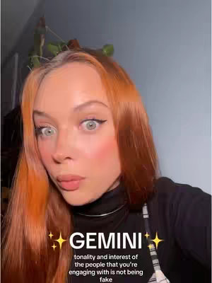A selfie-style image features a young woman with vibrant orange hair and light eye color. She is looking at the camera with a slight expression of surprise. Her cheeks are lightly blushed. Overlayed on the image is the word "GEMINI" in bold letters, along with additional text.