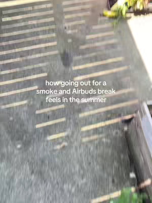 Overhead shot of a concrete surface with parallel lines of light and shadow, with some green vegetation visible at the edges. Text overlayed reads: "how going out for a smoke and Airbuds break feels in the summer".