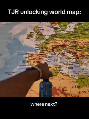 The cover image features a person's hand pointing at a world map, specifically towards the region of Spain and Italy. A blue water bottle is visible in the foreground. The map itself is detailed with country names and borders. Text overlays at the top and bottom of the image read "TJR unlocking world map:" and "where next?" respectively.