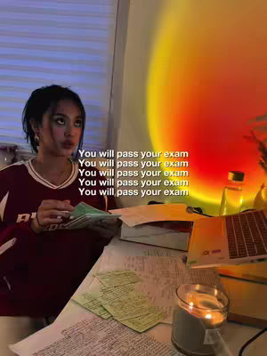 A young woman is sitting at a desk, looking up pensively with a stack of papers in her hand. The image has a warm color palette, the background features a warm gradient.