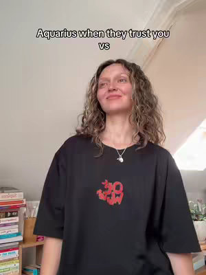 The cover image shows a woman standing in front of a wall, possibly indoors. Above her is text. She is wearing a black t-shirt with a red logo on it, a silver necklace, and her hair seems to be naturally curly.