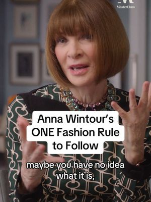 A medium shot features Anna Wintour, the subject. A text overlay reads: Anna Wintour's ONE Fashion Rule to Follow, with additional text: maybe you have no idea what it is. Anna Wintour is positioned slightly off-center, facing the camera. She wears glasses and a patterned green top. Her arms are raised, and her hair is in a bob hairstyle. The background is a soft, blurred interior with framed pictures.