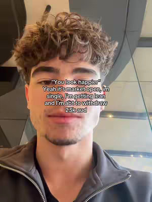 A selfie-style shot of a young man with curly brown hair, framed from the chest up. He is wearing a dark-colored top and has a slight smile. Text overlayed on the image reads, "You look happier," followed by details about his happiness.