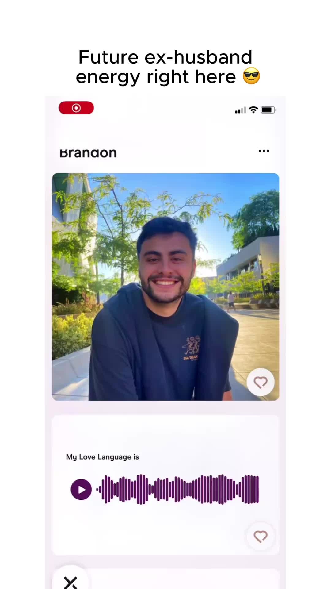 The image features a screenshot of the dating app interface, with a man's profile prominently displayed. The man, wearing a dark blue shirt, is smiling. The interface includes his name, 'Brandon', and a photo of him alongside details, and an audio spectrum element. The top of the screen features an overlaid text: 'Future ex-husband energy right here'. The image is set against a clean white background.