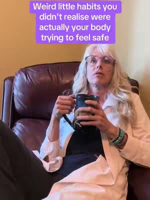 A woman with blonde hair and glasses is sitting in a brown armchair. She is holding a dark mug and looking upward with a slightly concerned expression. A text overlay in a purple box is at the top of the frame.