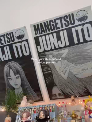 The image showcases a room with posters of Junji Ito's art. Beneath the posters are shelves filled with manga and figurines, and a shelf with accessories. The setting is a room that is lit by natural light.