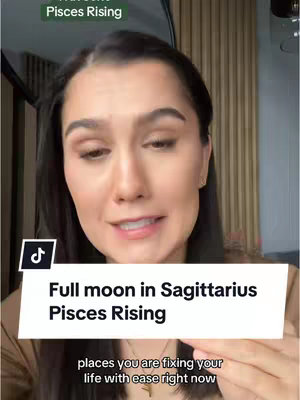 A woman with dark hair is centered in the frame, speaking directly to the camera. Above her head is a text overlay with the words "Full moon in Sagittarius Pisces Rising." Below, a white text box displays additional information about the video's message. The background appears to be a room with light-colored wooden paneling.