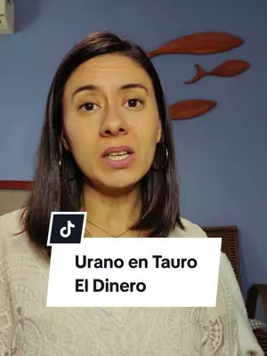 A woman with long brown hair, hoop earrings, and a light-colored top is facing the camera. Behind her, the wall has a blue color and wooden fish decorations. A white banner with black text is superimposed near her chest.