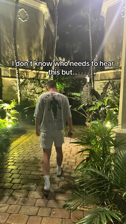 A nighttime shot of a man walking away from the camera down a brick path flanked by greenery. Text overlays the image.