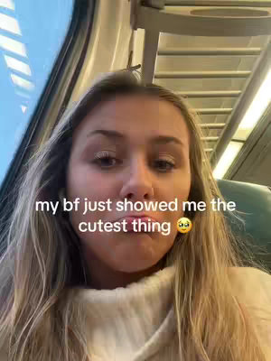 A woman with long blonde hair is in a train. She is looking at the camera. Text overlay says 'my bf just showed me the cutest thing' along with an emoji.