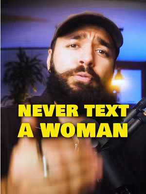 The image shows a man with a beard and a hat looking at the camera. The background has blurred lighting and a microphone is in the frame. There is overlaid text that says, "NEVER TEXT A WOMAN".