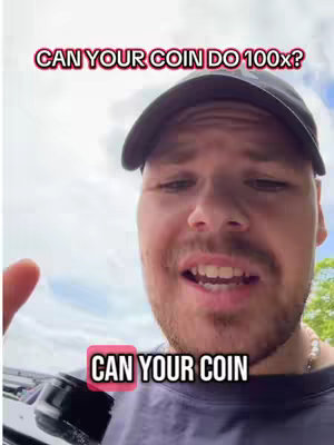 A man is in a medium shot, his face filling most of the frame, with a blurred background of a sky with clouds and some greenery. The man has short brown hair, a beard, and is wearing a black cap and a dark blue t-shirt. Text overlays appear on the top and bottom of the image. A device, possibly a camera or phone, is held out of frame in his hand, toward the lower left.