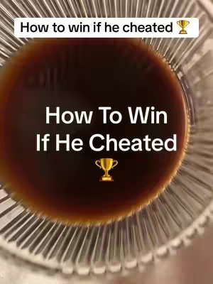 The image shows a close-up view of a glass with a dark liquid, likely coffee or a similar beverage. The liquid fills most of the frame, sitting inside a clear glass with vertical ridges. Overlaid on the liquid is a text overlay in white font, reading 'How To Win If He Cheated' with a trophy emoji. The composition has a shallow depth of field.