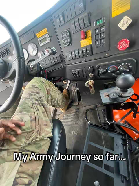 A first-person view inside of a military vehicle. The driver's legs clad in camouflage pants are visible, along with the steering wheel and dashboard, and text overlay that says, 'My Army Journey so far...'