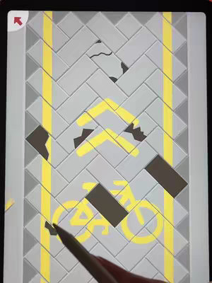 The image shows a section of a puzzle displayed on a tablet. The puzzle consists of grey, brick-like shapes arranged in a herringbone pattern. Yellow lines run vertically, suggesting a road or path. There are missing pieces, revealing a dark brown color within the puzzle. A yellow bicycle symbol is visible, formed by the puzzle pieces.