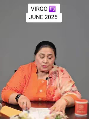 The image shows a woman sitting at a table, likely in a studio setting. Above her head is a white rectangle with the text 'VIRGO' and 'JUNE 2025' in black, along with the Virgo symbol. She is wearing an orange top with a patterned, peach-colored scarf. There is a pen and a red jar on the table, and her hands are positioned as if she's reading papers.