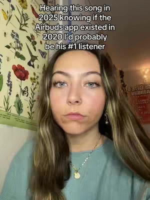 A young woman with long brown hair and a neutral expression is centered in the frame. She wears a teal top and a necklace. The background features a botanical print on canvas and a hint of some kind of decor. Text is overlaid at the top of the frame, in a white font, and is a conversational prompt.