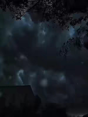 The image captures a moody, night-time scene. A dark, cloudy sky dominates the frame, with faint hints of blue peeking through the dense clouds. The silhouette of a building is visible in the lower portion of the image, and the silhouette of vegetation, possibly tree branches, is visible in the upper portion. The overall tones are dark blues and blacks, giving the image a mysterious and slightly ominous feel.