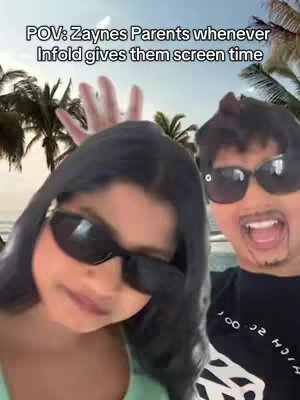 The cover image appears to be a selfie-style shot featuring two people, likely a couple or family members, in front of a beach or tropical background. They are both wearing sunglasses. The woman on the left is looking down and has long, dark hair. The man on the right is smiling with his mouth open. Text over the image reads 'POV: Zaynes Parents whenever Infold gives them screen time.' The background shows palm trees and a beach.