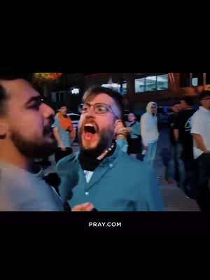 Two men are in an outdoor setting, one close-up with an open mouth and glasses, seemingly yelling. The other is partially visible on the left. Background features include a street scene with other people and buildings.