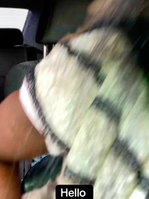 The image shows a blurred shot taken from inside a car. The focus is on the chest and arm of a person wearing a striped shirt. A text overlay with the word "Hello" in a black box is placed at the bottom. The composition evokes a sense of casualness.