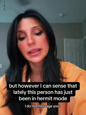 A woman with long black hair and orange top talks to the camera with text overlayed at the bottom.