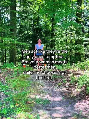 A woman wearing a blue shirt and shorts walks towards the camera along a tree-lined path in a forest. Text overlays the image.