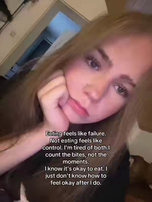 A selfie-style shot featuring a young woman with long blonde hair slightly out of focus, angled towards the upper-left corner. The woman is looking at the camera with a thoughtful expression, her hand resting near her face which is a soft pink blush.