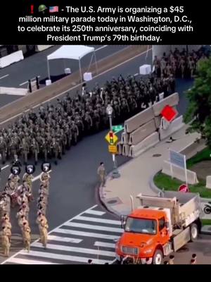 An aerial view of a military parade on a city street. Soldiers march in formation, and military vehicles are visible. The street has temporary concrete barriers along the side, and an orange truck is parked on the right. Text overlays at the top of the image provide context.