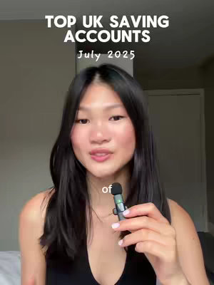 A vertical video still featuring a fair-skinned Asian woman with long, dark hair. She gazes slightly off-camera, holding a small black microphone. The background is a neutral, light gray, providing a subtle contrast to the woman. Text overlays at the top indicate the video's topic: "TOP UK SAVING ACCOUNTS" and "July 2025." The composition is simple, focusing on the woman and the informative text.