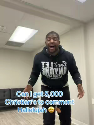 A man in a black hoodie is filmed indoors, with text overlays. The man is the central focus, standing and gesturing with excitement. Text overlays are placed at the bottom of the frame.