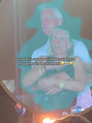The image features a couple embracing with a blurred effect, overlaid with text. A man is behind the woman, hands around her. The faces are slightly blurred, with the text appearing in a white font. The background suggests a concert, with lights and a large screen.