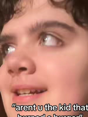 Close-up shot of a person's face, slightly angled to the right. They have fair skin, dark curly hair, and prominent eyebrows. The focus is on their eyes, which are looking upwards and slightly to the right. Their lips are slightly open, and there's a hint of a smile, and on the bottom of the screen there is a text written.